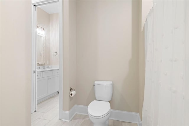 bathroom with baseboards, vanity, and toilet