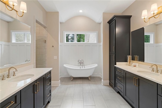 bathroom with a washtub, vanity, and vaulted ceiling