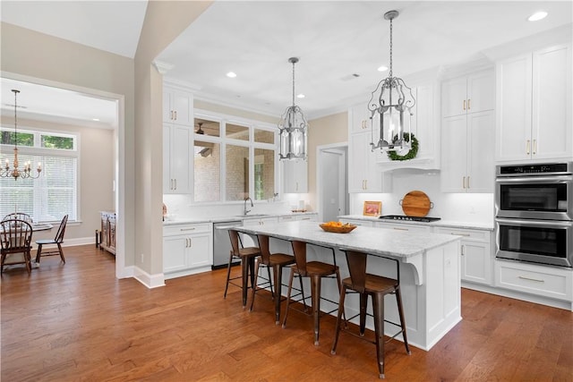 kitchen with sink, white cabinetry, stainless steel appliances, a center island, and a notable chandelier