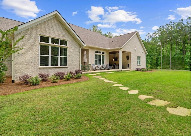 back of property with a patio area, brick siding, and a lawn