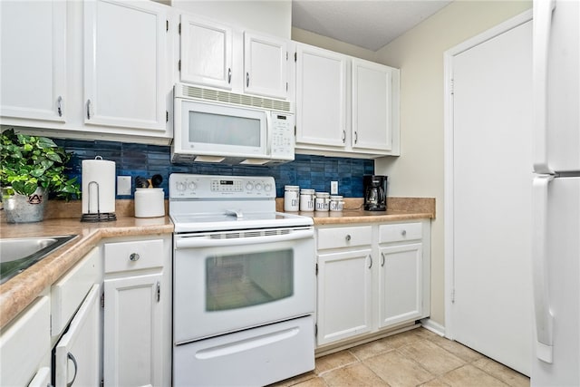 kitchen featuring white cabinets, light tile patterned flooring, white appliances, and backsplash