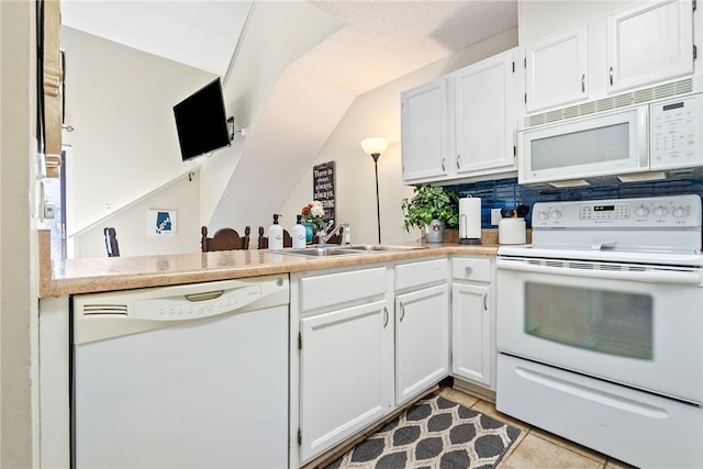 kitchen with sink, light tile patterned floors, kitchen peninsula, white appliances, and white cabinets