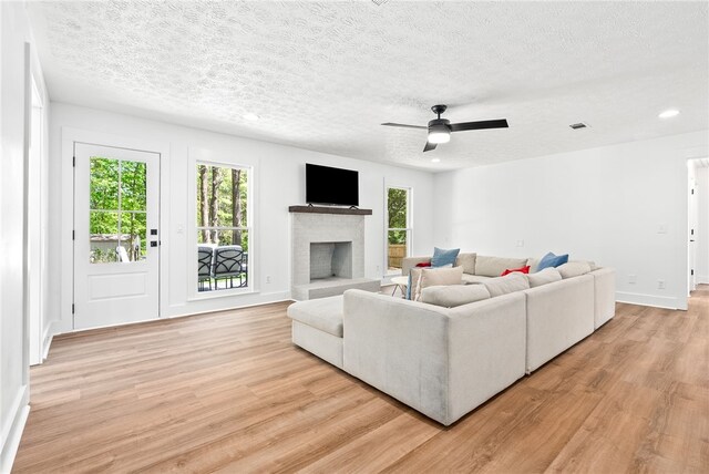 322 Cricket Ln, Auburn, AL 36832 - living area with light wood-style floors, healthy amount of natural light, a brick fireplace, a ceiling fan, and a textured ceiling