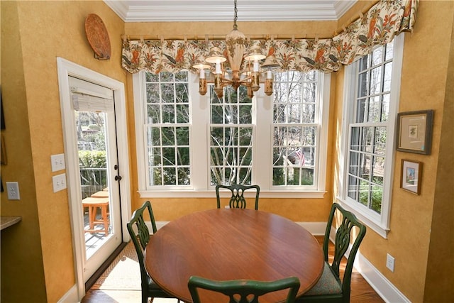 dining space with hardwood / wood-style floors, a notable chandelier, ornamental molding, and a wealth of natural light