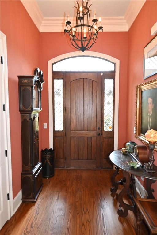 foyer entrance with a chandelier, dark hardwood / wood-style flooring, and ornamental molding