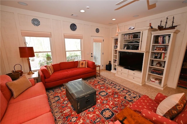 tiled living room with ceiling fan and built in features