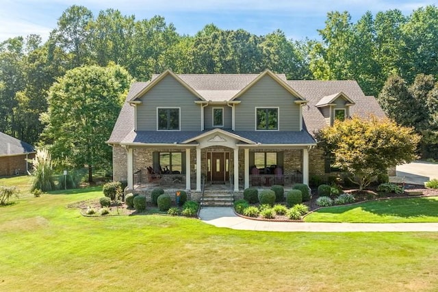 craftsman house with a shingled roof, covered porch, and a front lawn