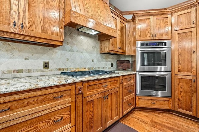 14699 Lee Road 188, Waverly, AL 36879 - kitchen with stainless steel appliances, brown cabinetry, custom range hood, and tasteful backsplash
