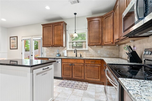 kitchen featuring a sink, decorative light fixtures, appliances with stainless steel finishes, light stone countertops, and visible vents