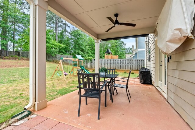 view of patio / terrace with a fenced backyard, outdoor dining space, a ceiling fan, and a playground