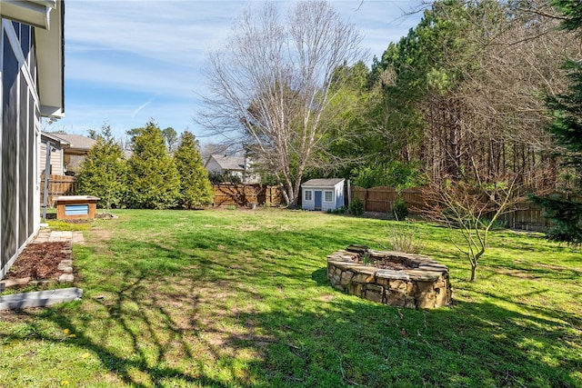 view of yard with a fire pit, an outbuilding, a fenced backyard, and a shed