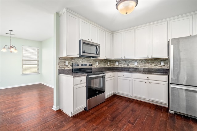 kitchen featuring dark wood-type flooring, backsplash, dark countertops, white cabinetry, and stainless steel appliances