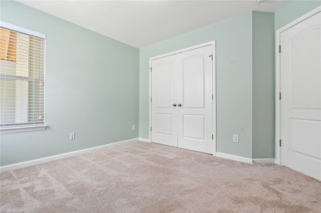 unfurnished bedroom featuring a closet, baseboards, and carpet