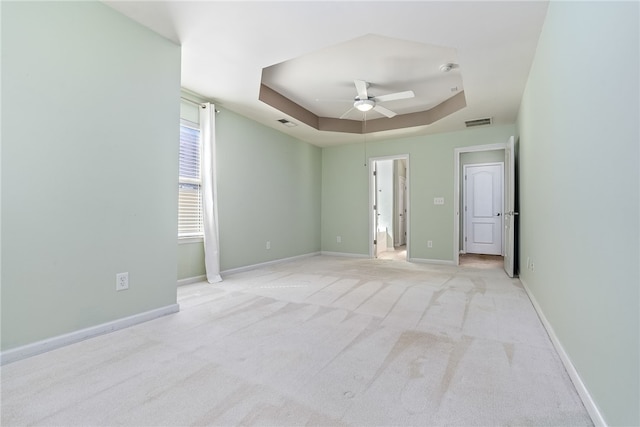 spare room with visible vents, a ceiling fan, baseboards, carpet flooring, and a raised ceiling