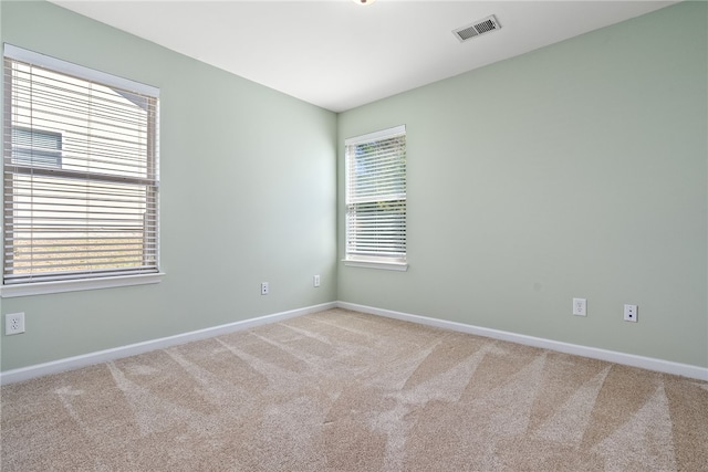 empty room featuring visible vents, baseboards, and light colored carpet