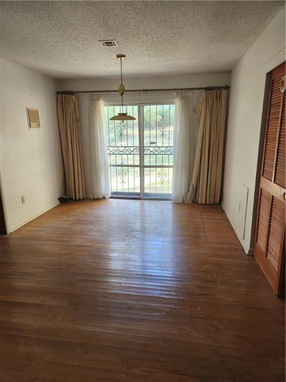 unfurnished room featuring dark hardwood / wood-style flooring and a textured ceiling