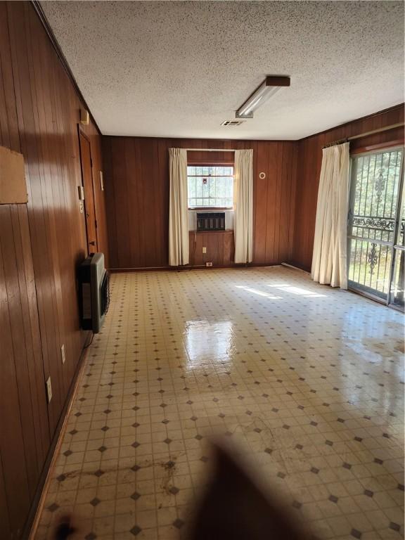 interior space with heating unit, wooden walls, and a textured ceiling