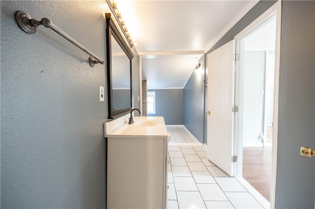 bathroom featuring tile patterned flooring, vanity, a textured wall, and ornamental molding