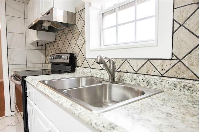 kitchen featuring under cabinet range hood, white cabinetry, a sink, and electric range