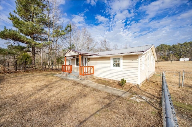 view of front of home featuring metal roof, a front yard, and fence private yard