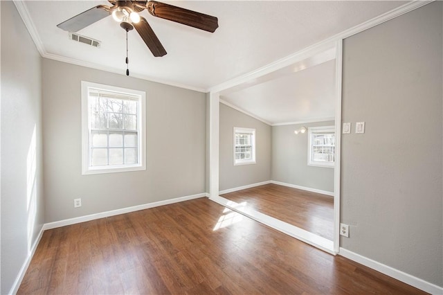 spare room with wood finished floors, baseboards, ornamental molding, and visible vents