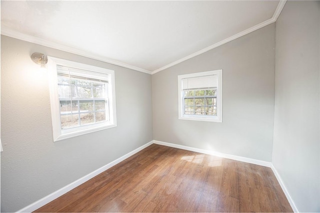 empty room with ornamental molding, vaulted ceiling, baseboards, and wood finished floors