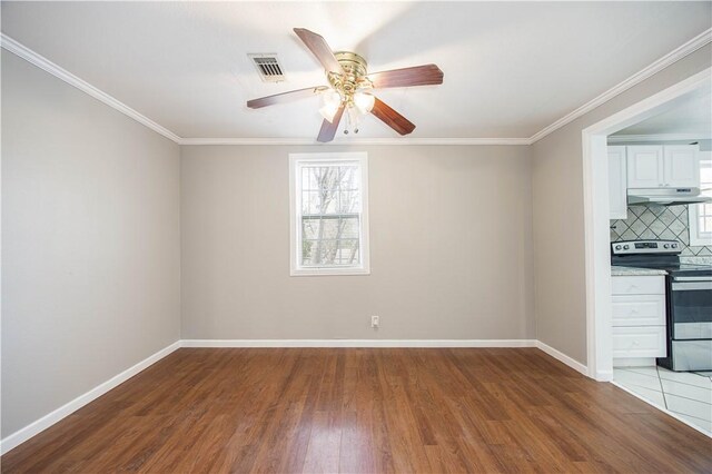 unfurnished room featuring ceiling fan, baseboards, wood finished floors, visible vents, and crown molding