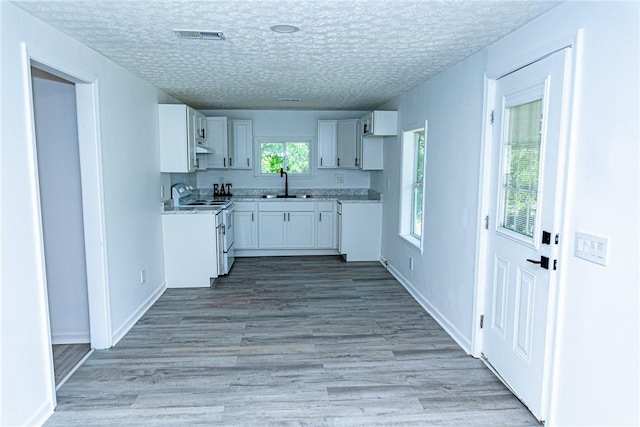 kitchen with light wood-style floors, white cabinets, a textured ceiling, and electric range