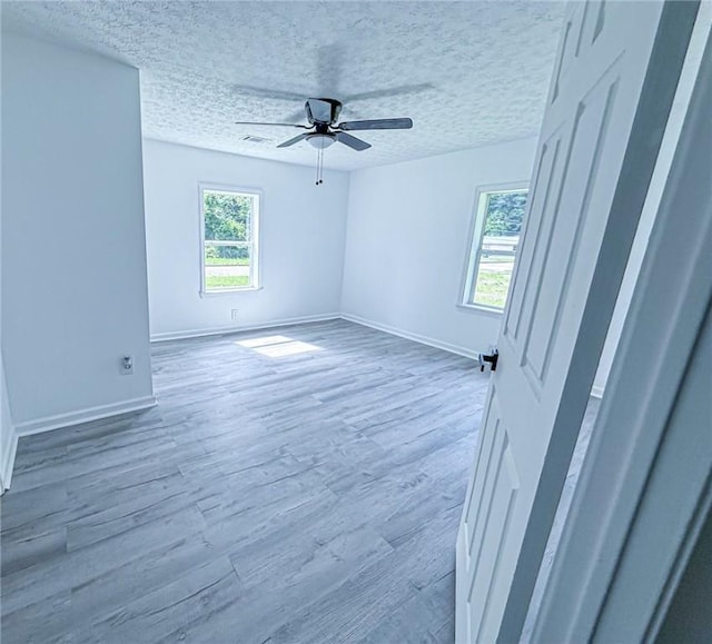 spare room with baseboards, a ceiling fan, visible vents, and wood finished floors