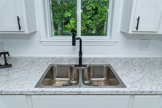 details with a sink and white cabinetry