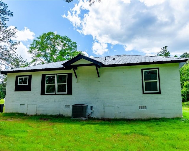 back of property with a lawn, metal roof, cooling unit, and crawl space