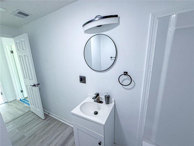 bathroom featuring vanity, baseboards, visible vents, and wood finished floors