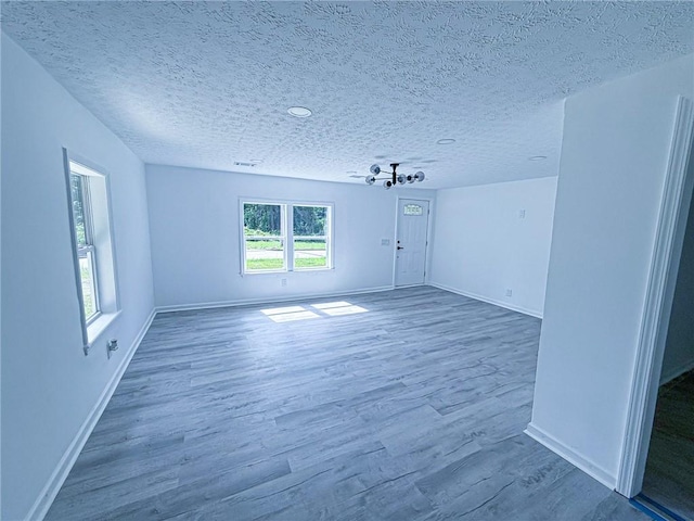 spare room featuring a textured ceiling, baseboards, and wood finished floors