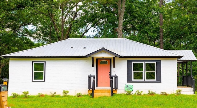 ranch-style home featuring metal roof, a front lawn, and brick siding