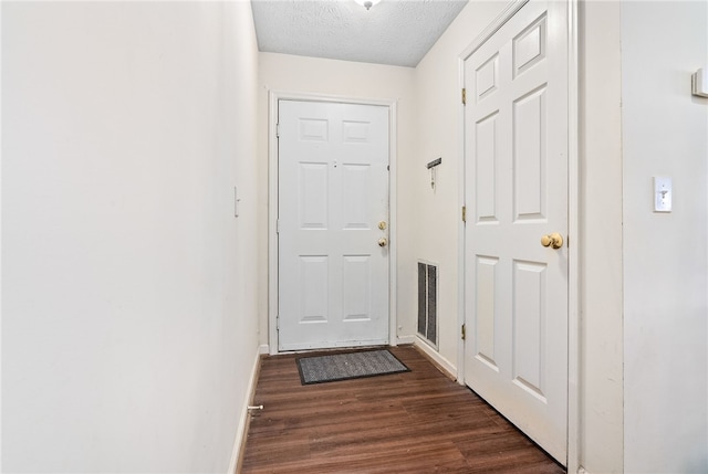 doorway to outside with dark hardwood / wood-style floors and a textured ceiling