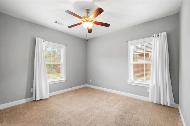 spare room with light carpet, ceiling fan, and a healthy amount of sunlight