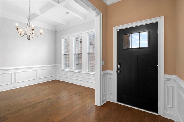 entrance foyer with dark hardwood / wood-style floors, beam ceiling, an inviting chandelier, and coffered ceiling