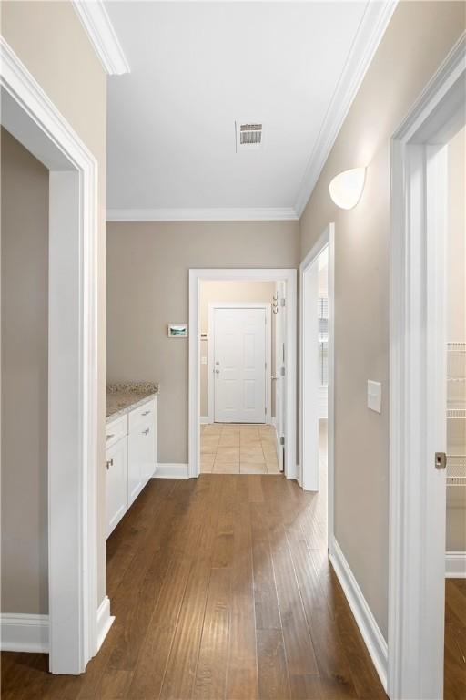 corridor with hardwood / wood-style flooring and ornamental molding