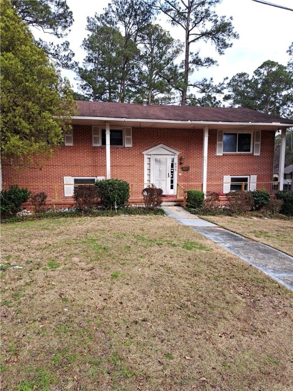 raised ranch with brick siding and a front lawn