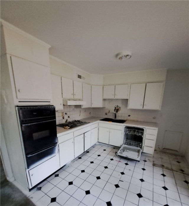 kitchen featuring light countertops, gas stovetop, white cabinetry, a sink, and black oven