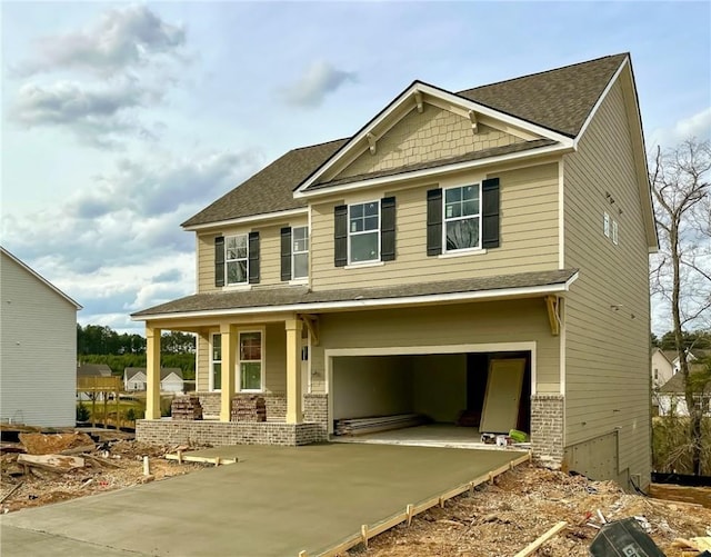 craftsman house with a garage, brick siding, driveway, and roof with shingles