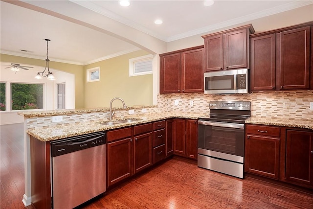 1931 Sequoia Dr, Auburn, AL 36879 - kitchen featuring appliances with stainless steel finishes, a peninsula, dark wood-style floors, light stone countertops, and ornamental molding