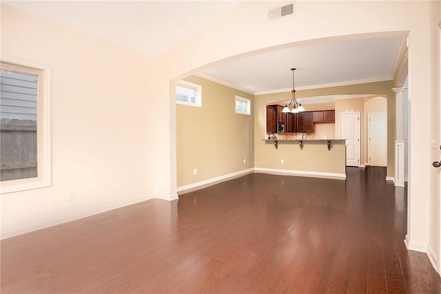 1931 Sequoia Dr, Auburn, AL 36879 - unfurnished living room with arched walkways, dark wood-style flooring, ornamental molding, and a chandelier