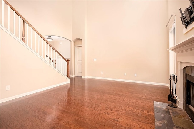 1931 Sequoia Dr, Auburn, AL 36879 - unfurnished living room featuring a high ceiling, wood finished floors, a fireplace, arched walkways, and stairs