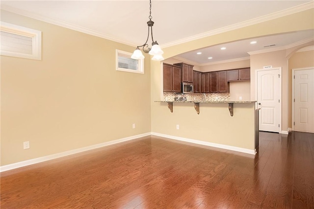 1931 Sequoia Dr, Auburn, AL 36879 - kitchen with stainless steel microwave, a breakfast bar, a peninsula, arched walkways, and light stone counters