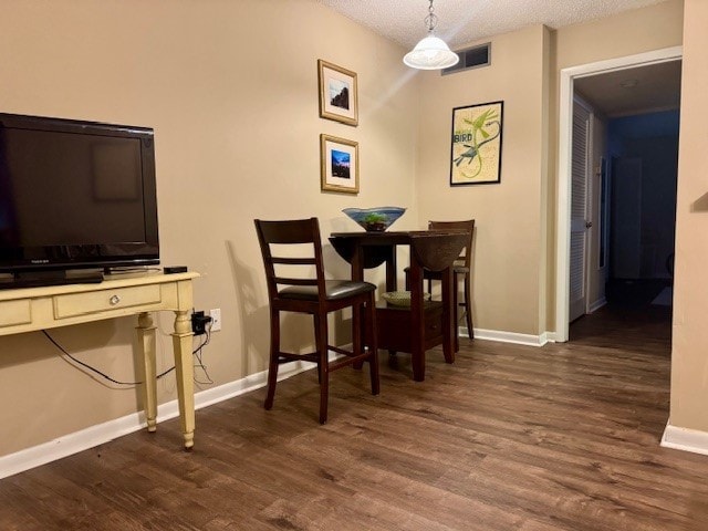 dining room featuring dark wood-type flooring, a textured ceiling, and baseboards