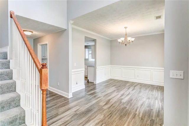 2331 Morgan Dr, Auburn, AL 36830 - spare room featuring wood finished floors, stairway, a chandelier, crown molding, and wainscoting
