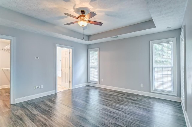 2331 Morgan Dr, Auburn, AL 36830 - unfurnished bedroom featuring a walk in closet, a tray ceiling, dark wood finished floors, a closet, and ceiling fan