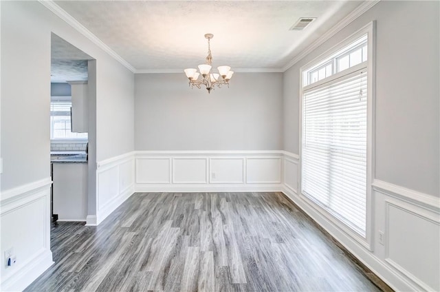 2331 Morgan Dr, Auburn, AL 36830 - unfurnished dining area with a chandelier, wood finished floors, healthy amount of natural light, wainscoting, and a decorative wall