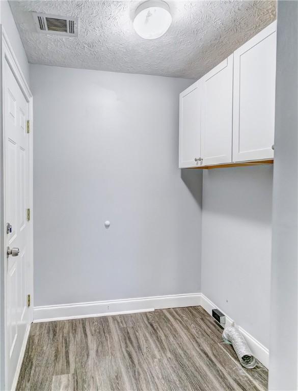 2331 Morgan Dr, Auburn, AL 36830 - laundry area featuring cabinet space, wood finished floors, and a textured ceiling